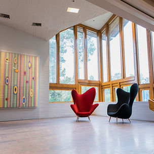 Two armchairs and an acrylic painting by Hans-Christian Berg decorates a stairs landing in Dipoli, Aalto University