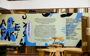 A large printed ARTEFAKTI presentational panel with artists' names and exhibition text