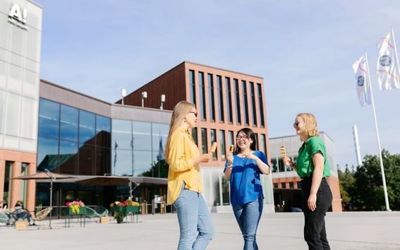 Three women talking and eating ice cream in front of the Väre building. 