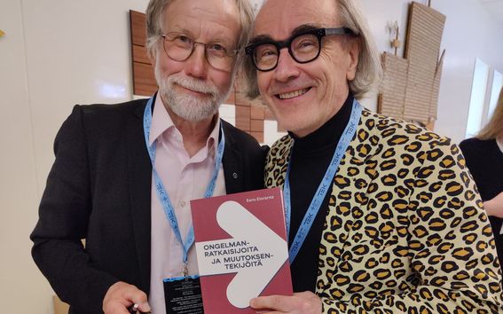 Eero Eloranta and Esa Saarinen holding the new history book of industrial engineering written by Eero Eloranta. 