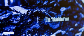 Detail of an artwork. Blue surface with blurry text.
