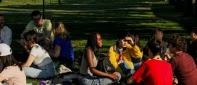 Aalto-yliopiston kesäkoulun opiskelijat viettämässä aikaa yliopiston kampuksen ulkopuolessa oleva puistossa.