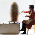 Professor Maarit Mäkelä sits on a chair and paints a ceramic pot with soil from Venice, in a brightly lit area