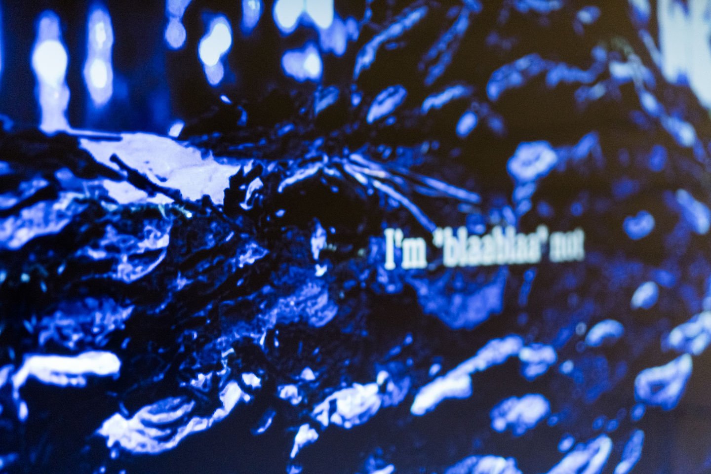Close up of a digital piece showing swirls of blue and some fictional text laid over the top