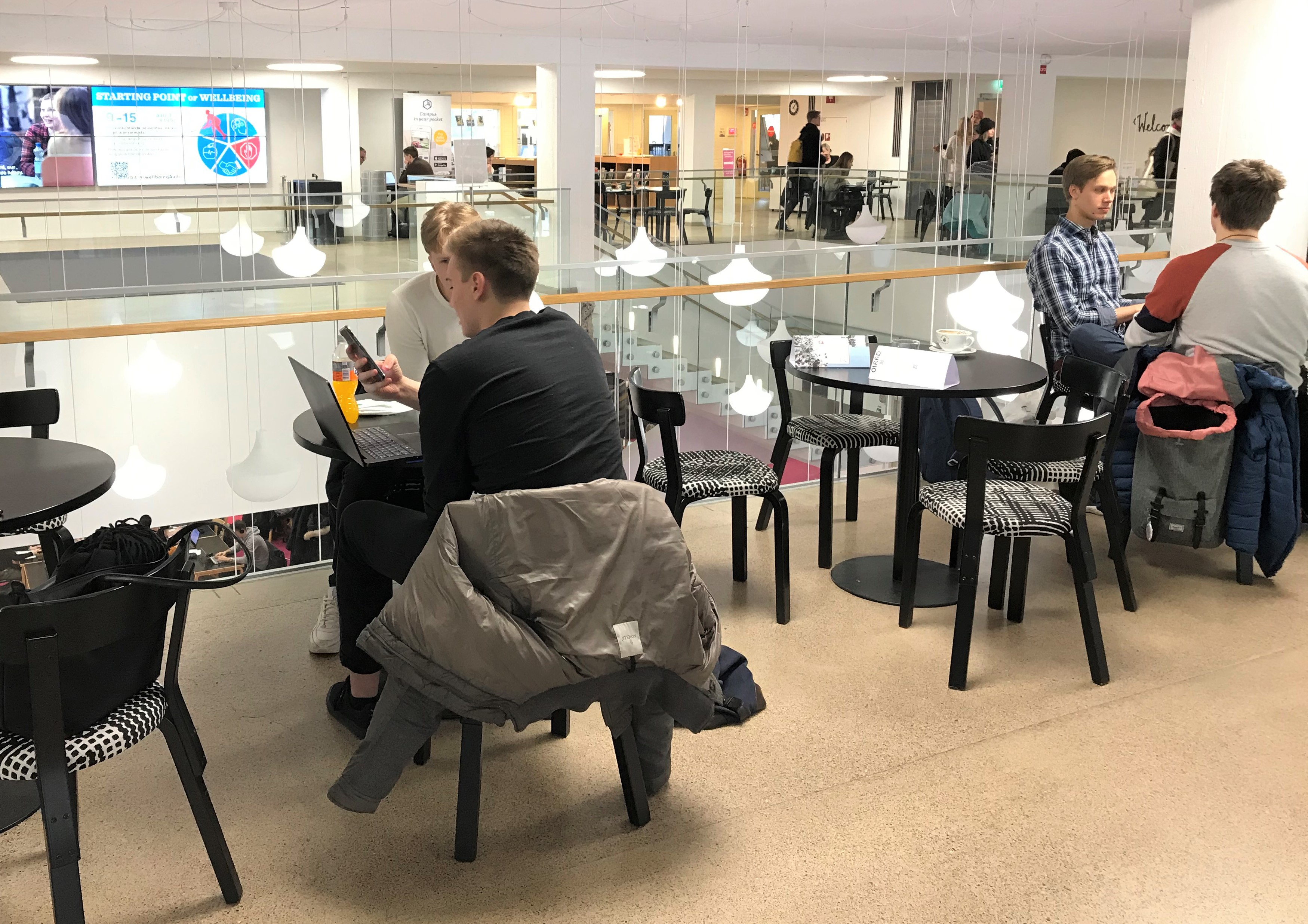 Valokuva Oppimiskeskuksen 1. kerroksen kahvilasta, jossa on asiakkaita.