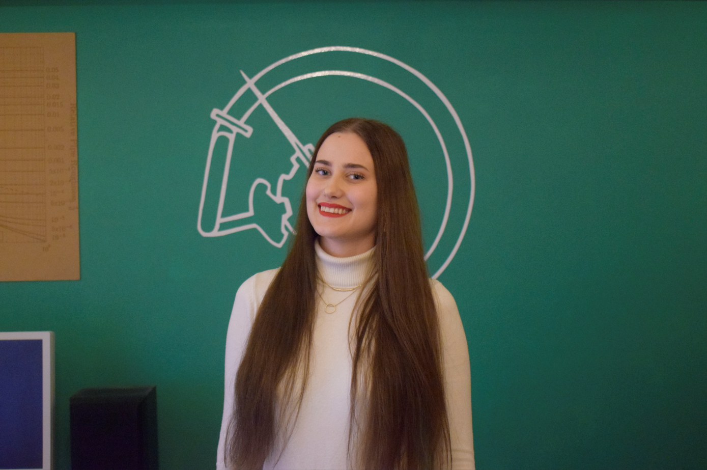 Mariina Tikka hymyilee kameralle, taustalla vihreä seinä.