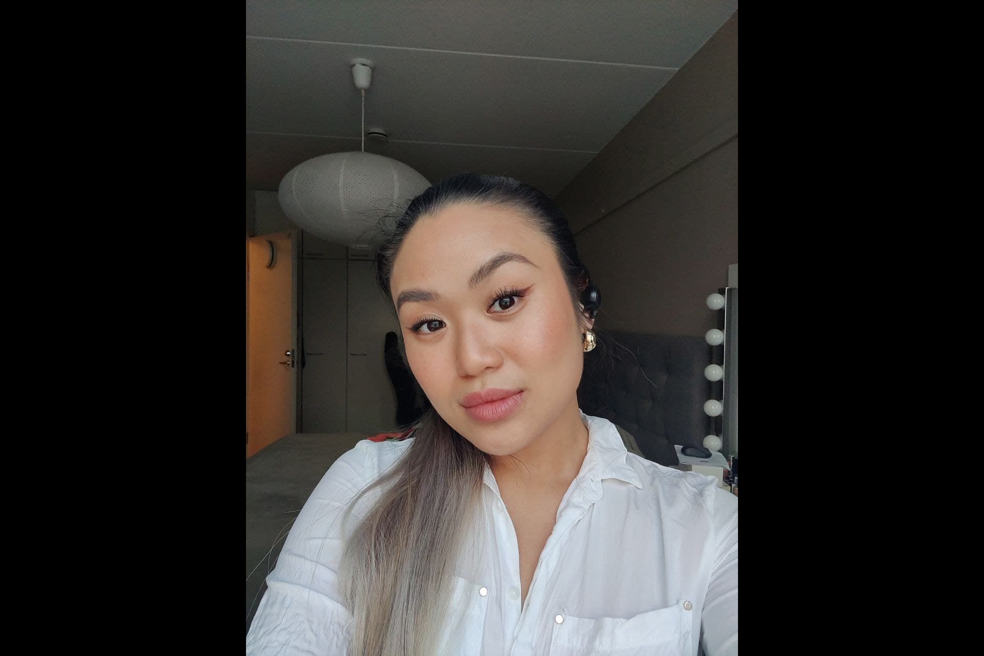 Mimi Tran kuvattuna asunnossa, itseottama kuva. Taustalla kattolamppu ja vasemmalla avoin ovi.