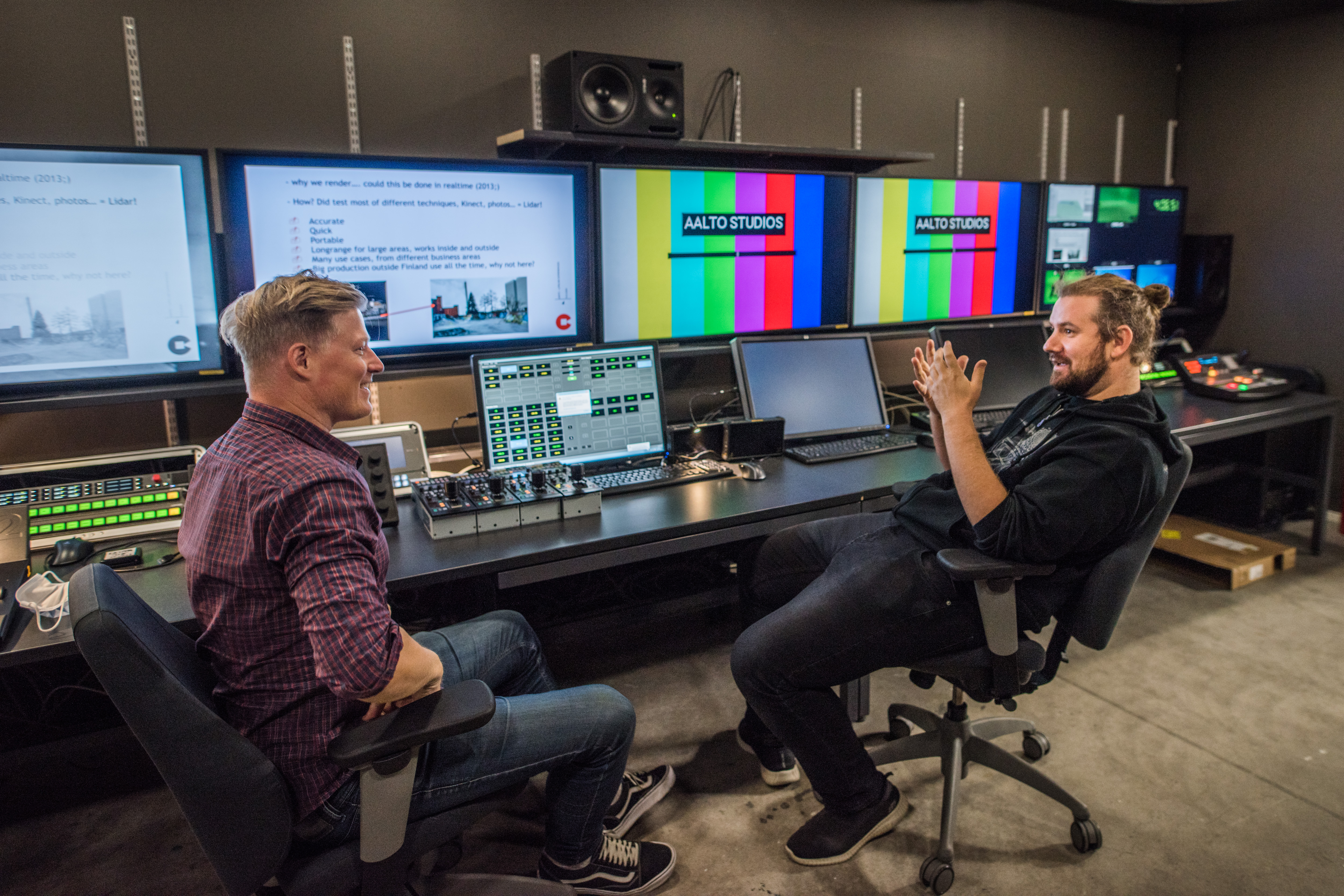 Two people sit facing each other by a large editing table, intensily interacting with each other