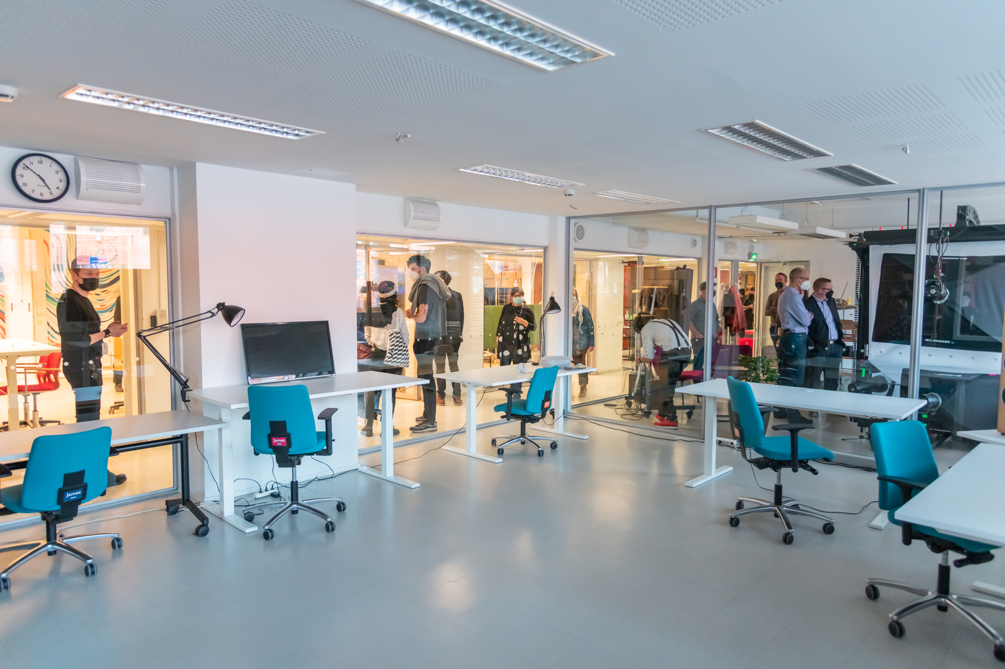 Space 21 corridors full of people, picture taken from the empty room through glass walls.