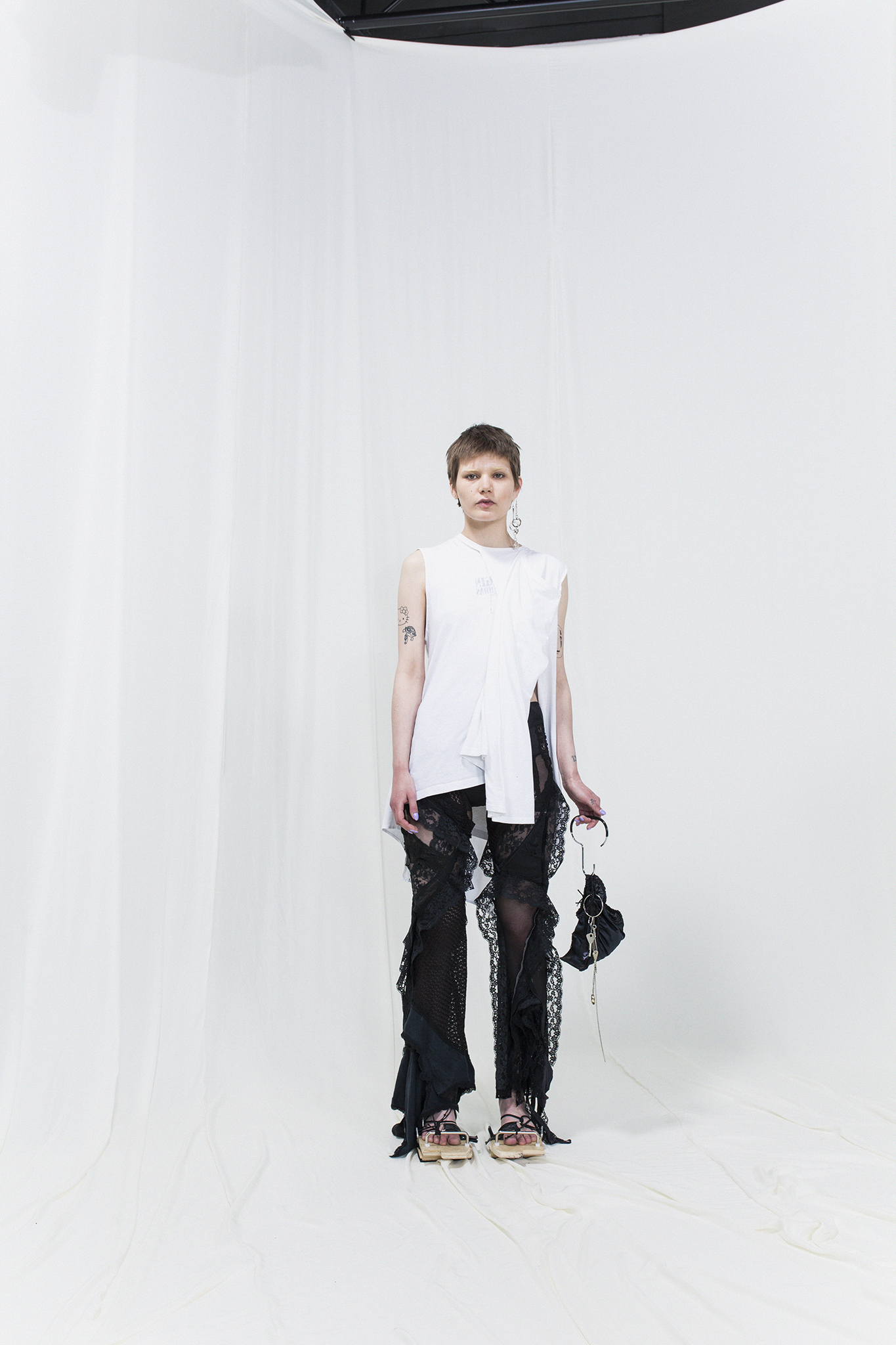 Photo of a person wearing a designer outfit: white top and black trousers and holding a black handbag