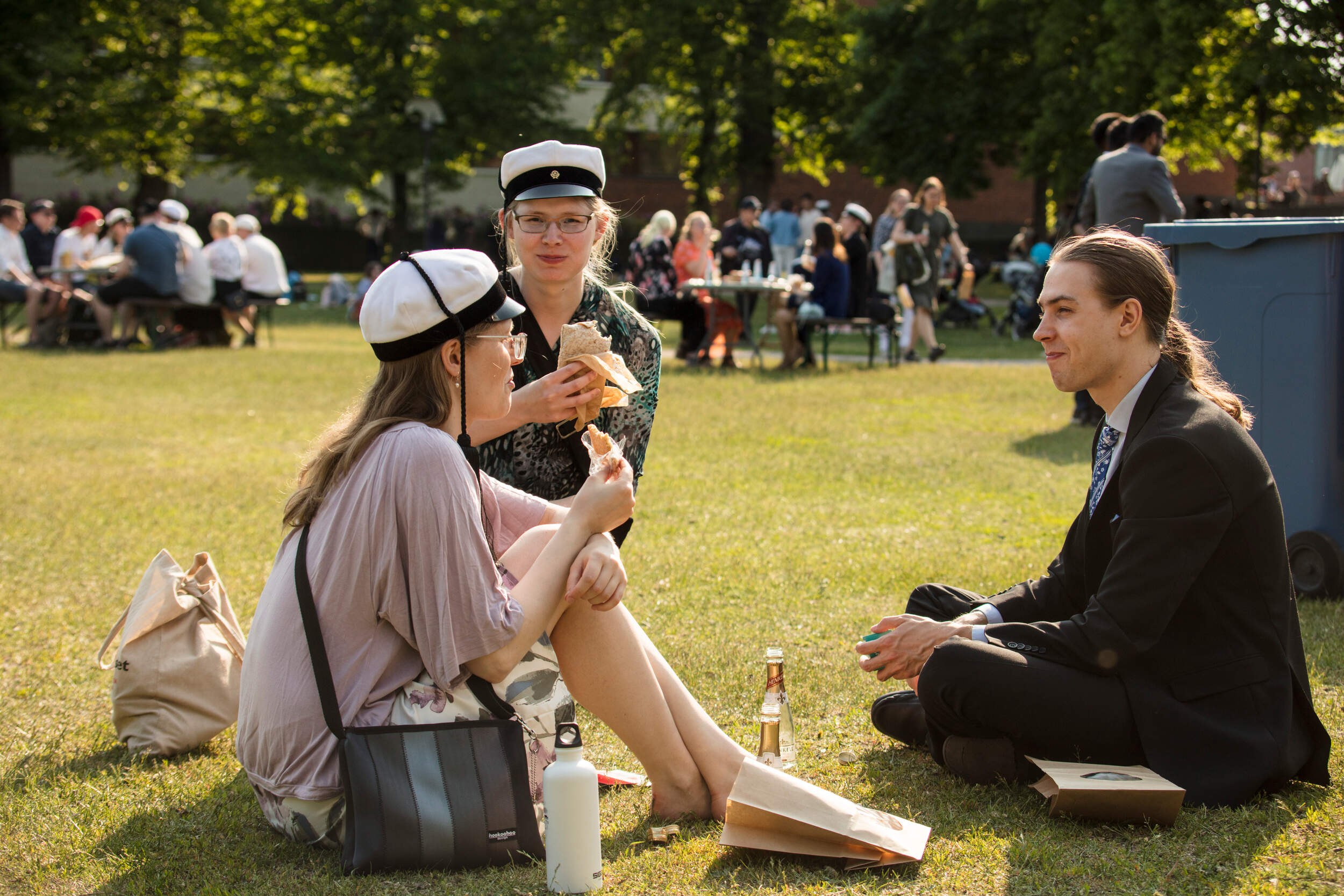 Three graduates sitting and having a picnic at the park