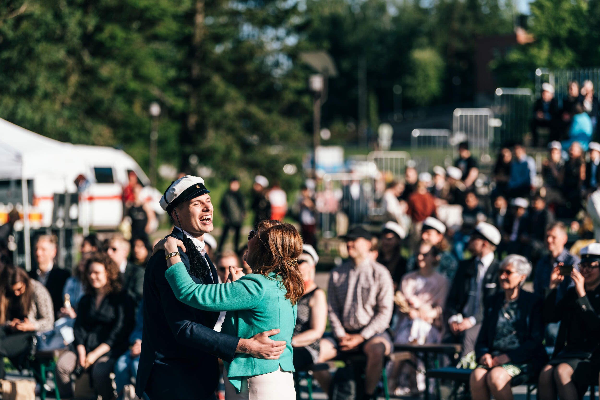 A couple dancing and laughing, rows of graduates on the background