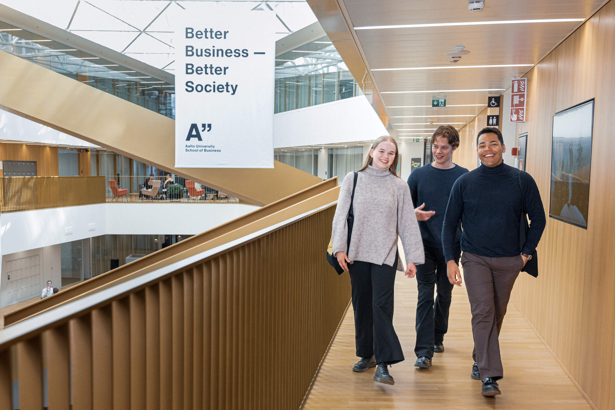 Three students walking in the school corridor side by side and talking