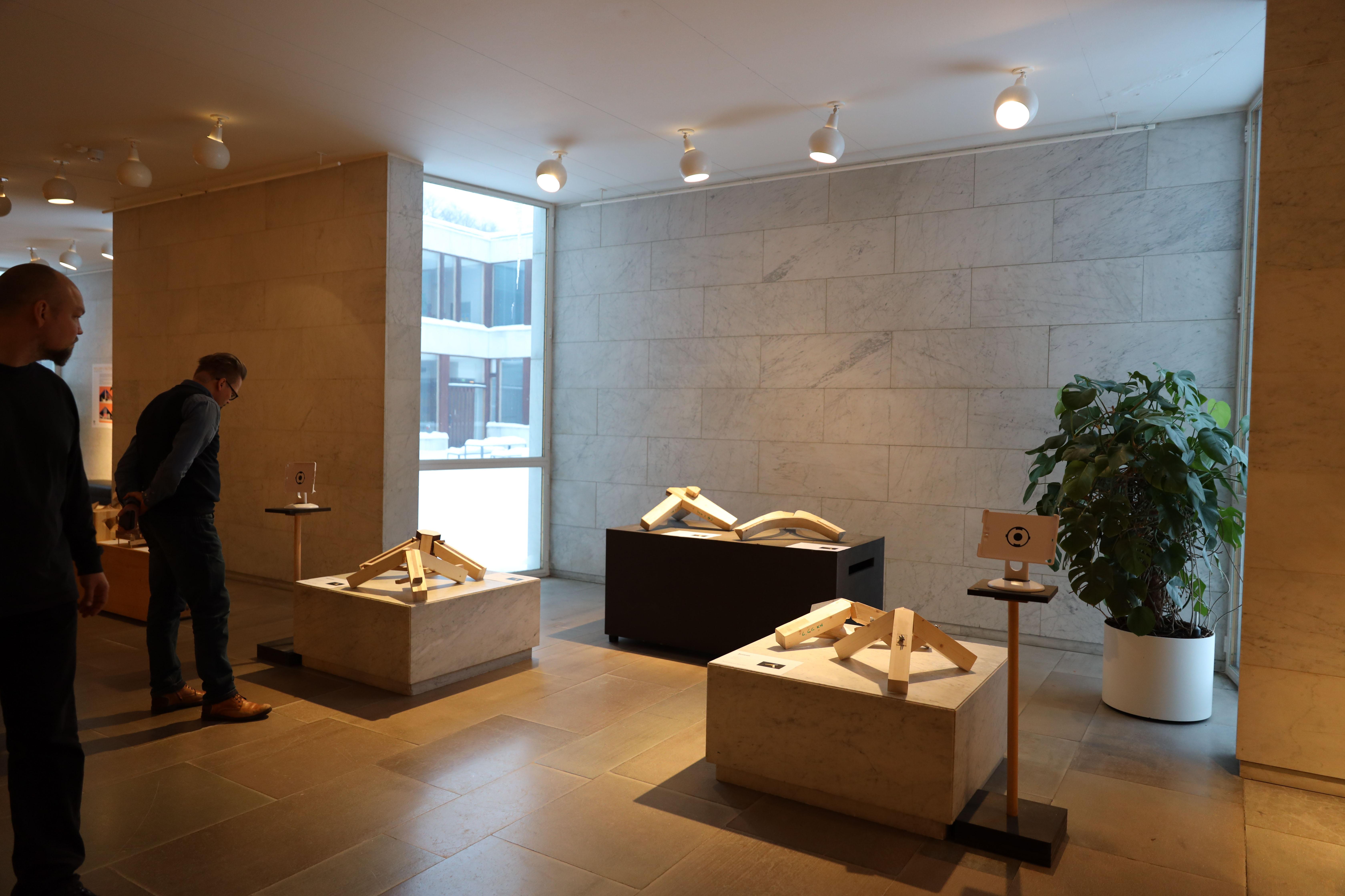 Wooden joint tripods standing on marble plinths in the exhibition space