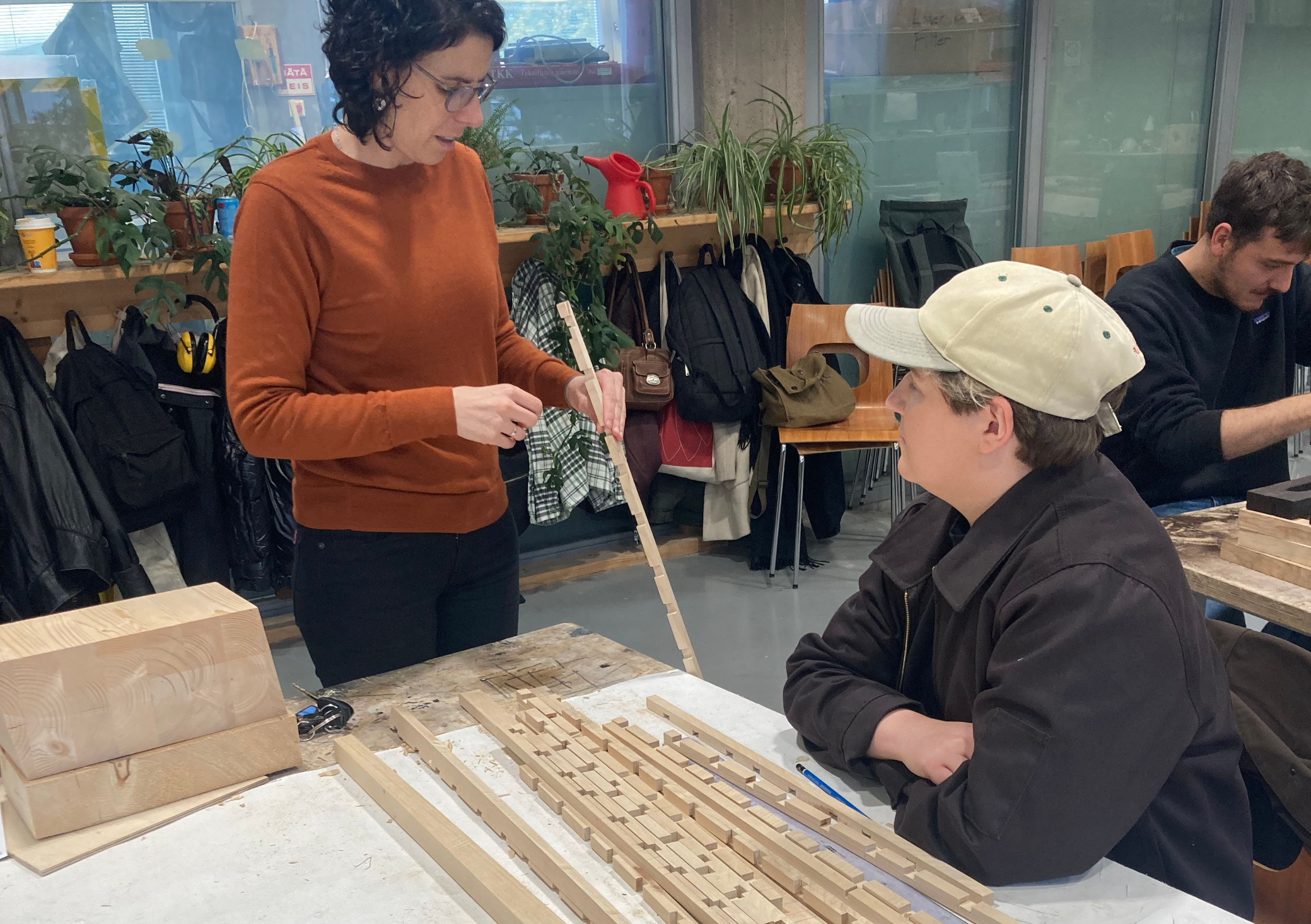 Student and teacher discussing around a pile of square wood dowels