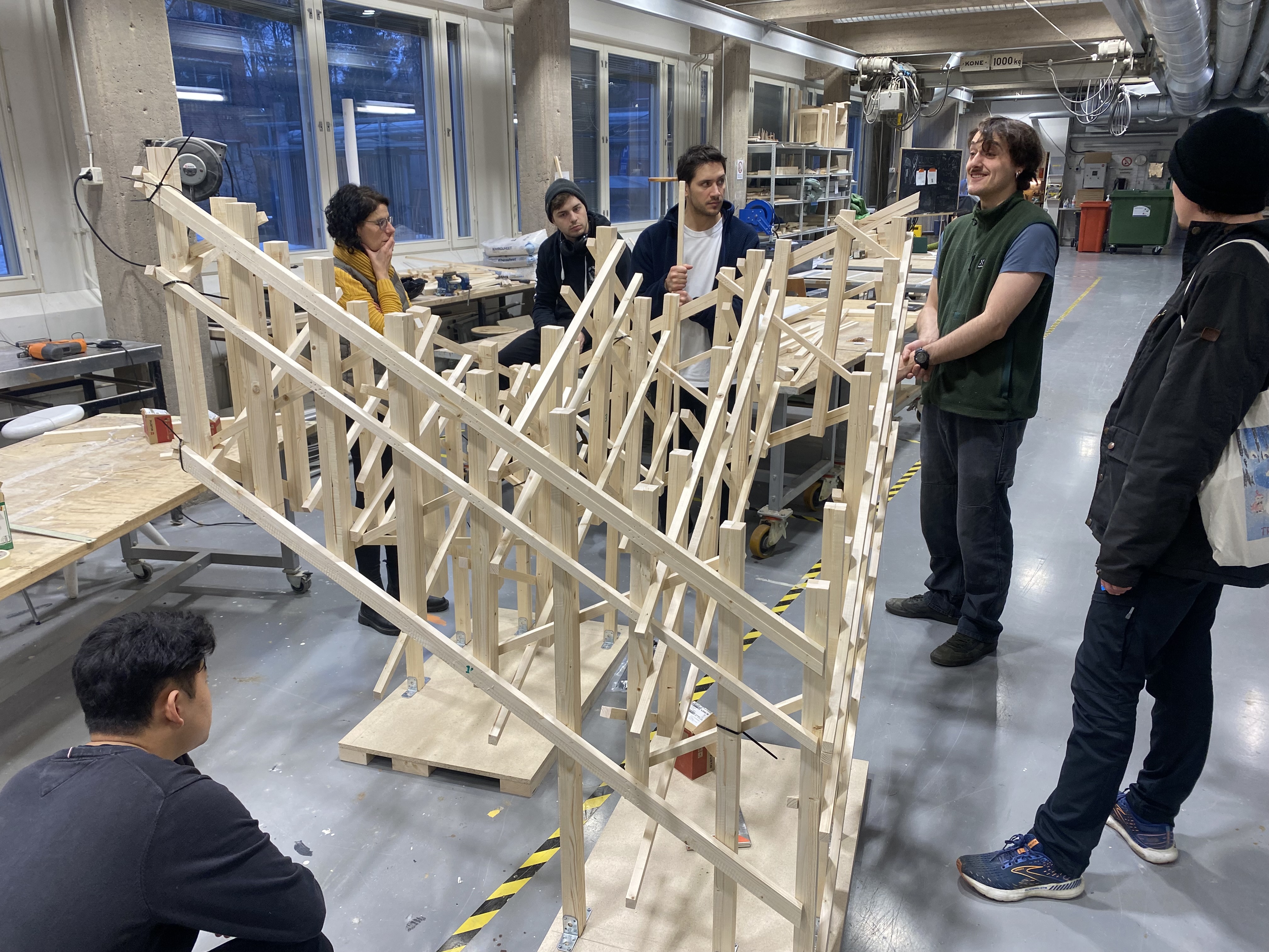 Students and teachers standing around 1 to 5 model discussing assembly strategies
