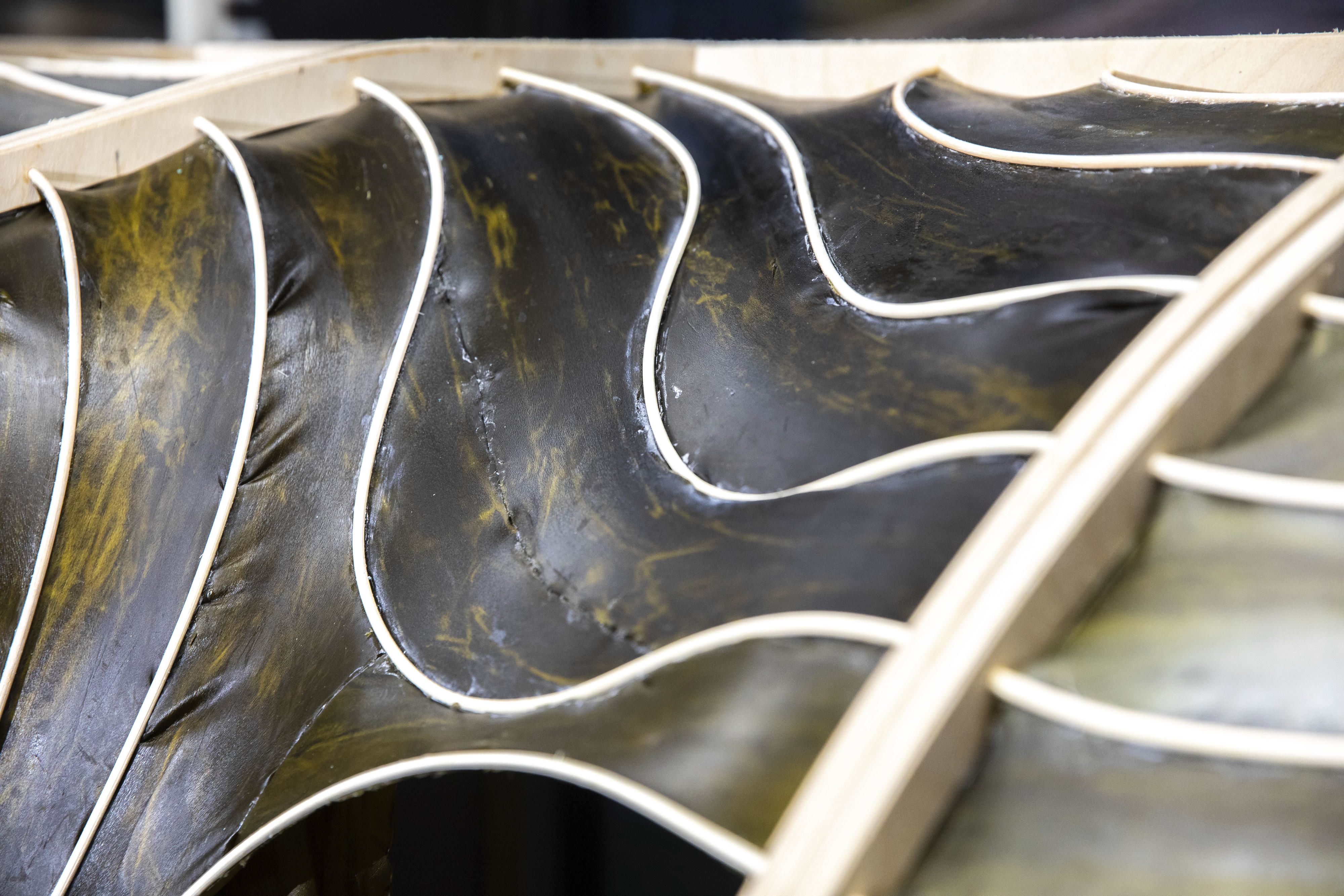 Close-up of a curved, black and gold structure with white edges, resembling abstract waves or fins.