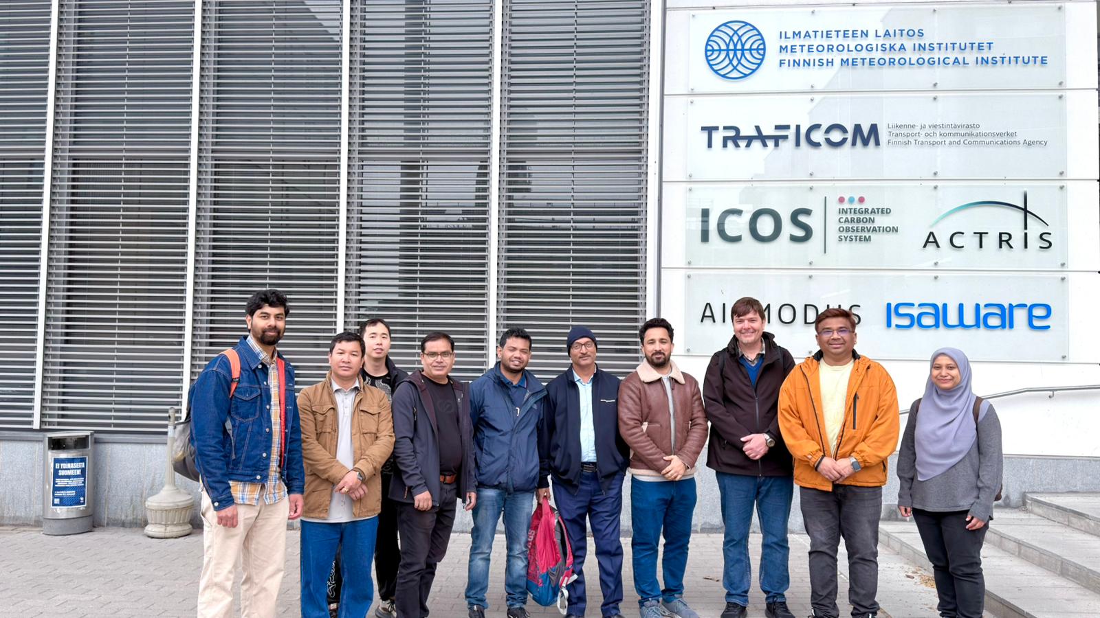 Group of people in jackets standing outside Finnish Meteorological Institute building with logo signs