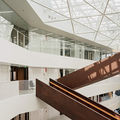 Väre building in the campus. Inside shot of natural light filled dark wood staircase criss-crossing in white surroundings. Light through skylights. Photo by Aalto University / Tuomas Uusheimo