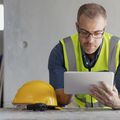 A man uses a tablet computer at a construction site.