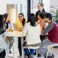 Smiling people sitting and standing around a table.