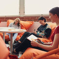 Three people doing group work; sitting in bean bags, smiling and writing post-it notes