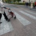 A person crossing a street with a rollator