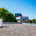 A large white 'A!' sculpture on the rooftop of the Undergraduate centre. A large tree and other buildings in the background.