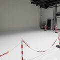 A photography studio with white walls and floor, bordered off with red and white chains.