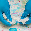 White Ioncell-F fibre being handled over a colourful cellulose aquarelle.