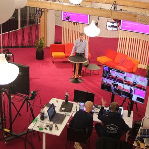 Man in the middle of a studio leaning on a table. Studio equipment showing.