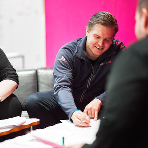 Opiskelijat istuvat pöydän ääressä ja tekevät yhdessä muistiinpanoja.