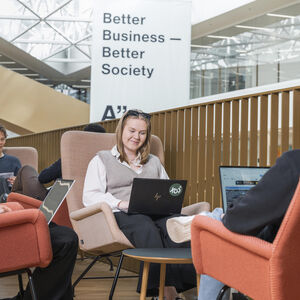 Opiskelijat istuvat nykyaikaisissa tuoleissa, työskentelevät läppäreillä kyltin alla, jossa lukee Better Business.