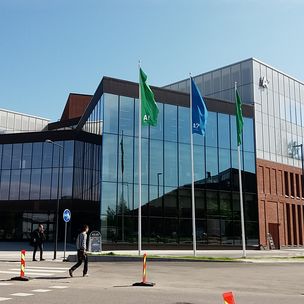 Outside picture of the School of Business building in Otaniemi. Three Aalto Flags swinging in front of the building.