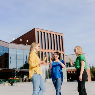 Three women talking and eating ice cream in front of the Väre building. 