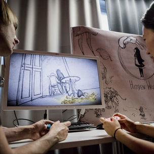 Two people discussing about a scetch they are looking on a computer