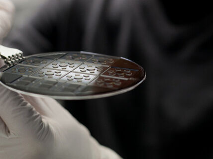 Close-up on a pair of hands wearing white rubber gloves, holding a black plastic coaster.