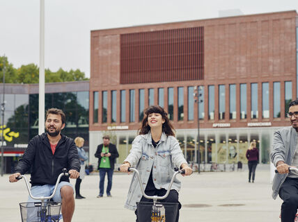 Students riding bikes in front of the Aalto University Väre building, photo by Unto Rautio