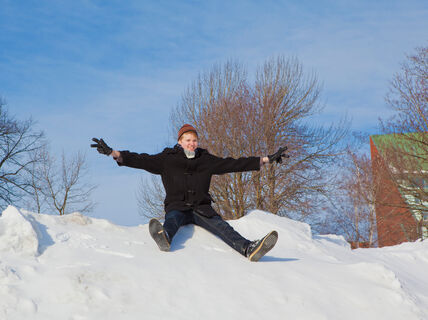 Lumikinos. Opiskelija laskee mäkeä Alvarin aukiolla. Taustalla kandidaattikeskus.