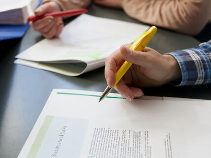 Two people taking notes on an article