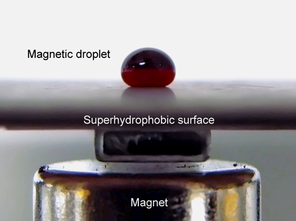 A ferrofluid droplet sitting on a measurement surface in the oscillating droplet tribometer measurement scheme. The magnet underneath the surface is also seen.
