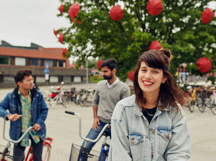 Three students with bicycles in front of Väre building, Aalto University