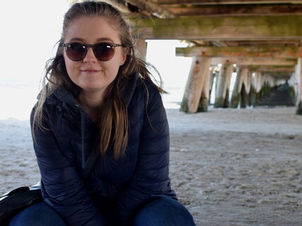 Aalto University / A girl sitting on sand with sunglasses on / Laura McLeod