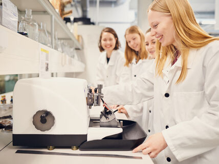 Students looking at a microscope smiling