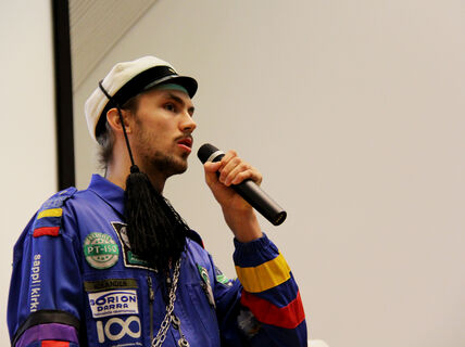 An image of Rudolf speaking into a microphone