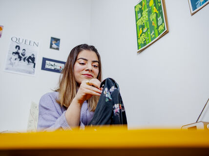 Marium Durrani ompelemassa käsin vaatekappaletta, jossa on kukkakuosi.