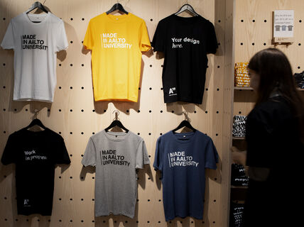Colorful Made in Aalto University -t-shirts hanging at Aalto University Shop's wall