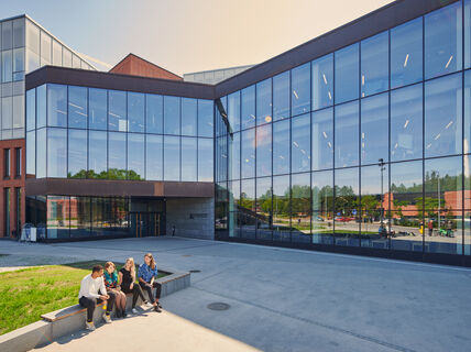 Kauppakorkeakoulu, jonka edustalla istuu neljä opiskelijaa. Kuva: Unto Rautio / Aalto-yliopisto