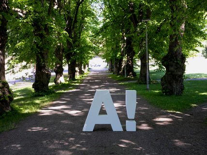 Aalto logo placed at campus on green pathway, photo by Mikko Raskinen 