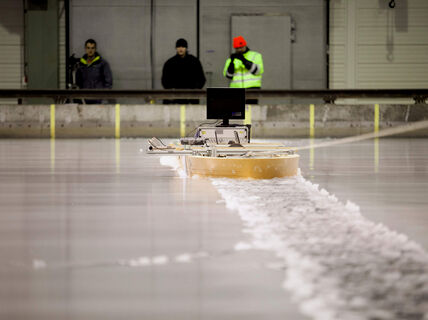 Three researchers using a device on the surface of the ice at Aalto ice tank